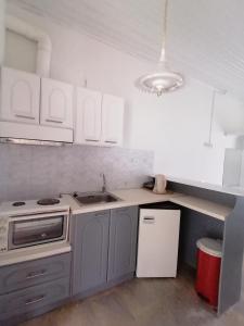 een keuken met witte kasten, een wastafel en een koelkast bij Nikos Apartments in Acharavi