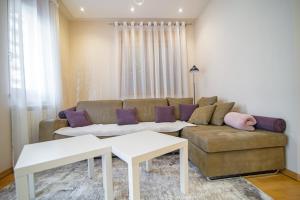 - un salon avec un canapé brun et des oreillers violets dans l'établissement Luxury Kalman Centar Apartmani, à Zlatibor