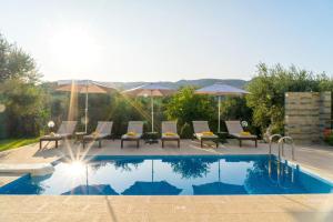 una piscina con sillas y sombrillas junto a ella en Villa Chrissi, en Kissamos