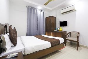 新德里的住宿－Ratandeep International，一间卧室配有一张床、一把椅子和电视