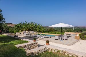 um quintal com uma piscina e um guarda-sol em Villa Balatella con Piscina by Wonderful Italy em Augusta