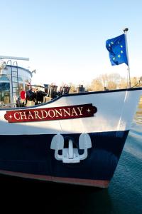 a boat in the water with a sign on it at Bateau Hotel à quai Le Chardonnay in Avignon