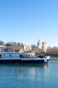 a boat on the water with a city in the background at Bateau Hotel à quai Le Chardonnay in Avignon