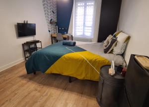 - une chambre avec un lit doté d'une couverture jaune et bleue dans l'établissement Studio Bon pasteur hyper centre Aix, à Aix-en-Provence