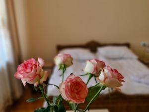 a vase with pink roses in front of a bed at Guest House David's B&B in Gyumri