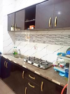 a kitchen counter with a stove and a sink at Bravo Apartment, Awka in Akwa