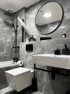 ein Badezimmer mit einem weißen Waschbecken und einem Spiegel in der Unterkunft Penthouse Birmingham City View in Birmingham