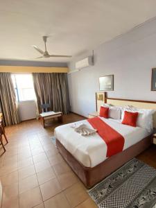 a hotel room with a large bed with red pillows at Gaborone Hotel in Gaborone