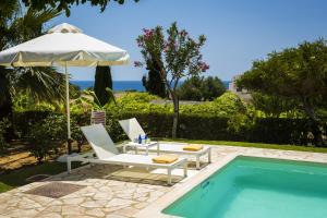 ein Pool mit zwei Stühlen und einem Sonnenschirm neben einem Pool in der Unterkunft Xenia Villa in Argostoli