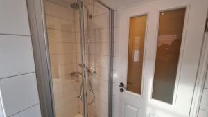 a bathroom with a shower with a glass door at Ferienhaus-Sommerwind in Neßmersiel
