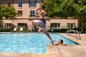 a woman jumping into a swimming pool with a boy at Hyatt Regency Sonoma Wine Country in Santa Rosa