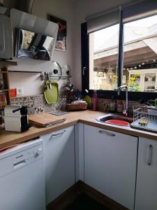uma cozinha com armários brancos, um lavatório e uma janela em Gîte la comète em Chinon