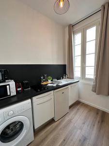 a kitchen with a washing machine and a washer at Les Arches 1 in Saintes