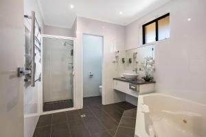 La salle de bains est pourvue d'une baignoire, d'un lavabo et d'une douche. dans l'établissement Comfort Inn May Park, à Horsham