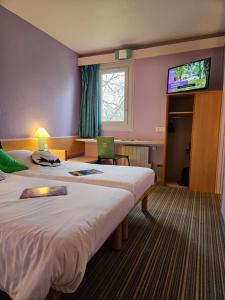 a hotel room with two beds and a flat screen tv at Hotel Bonanite in Villers-Cotterêts