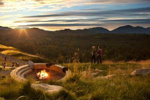 two people standing next to a fire pit in a field at Suncadia Resort in Cle Elum