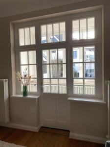 a room with a door with windows and a vase with flowers at Ferienhaus ON90 in Wilhelmshaven