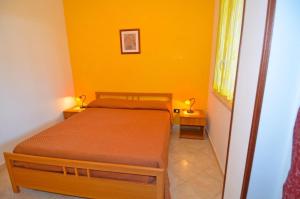 a small bedroom with a bed and a yellow wall at Ippazio 2 in Marina di Pescoluse