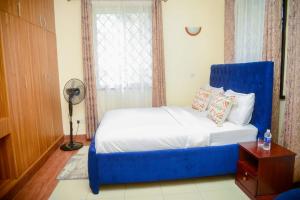 a bed with a blue chair in a room at Kothuondo's 2 &3edrooms all ensuite apartment in Kisumu