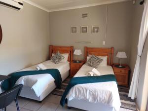 two beds in a room with two tables and two lamps at UNIQUE BnB in Vryheid
