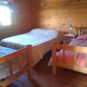 1 dormitorio con 2 camas en una cabaña de madera en Cabañas Los Piamonteses Cosmopolita, en Juan L. Lacaze