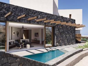 an external view of a house with a swimming pool at Magma Resort Santorini, In The Unbound Collection By Hyatt in Vourvoulos