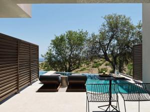 un patio con mesa, sillas y piscina en Magma Resort Santorini, In The Unbound Collection By Hyatt, en Vourvoúlos