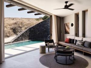 un soggiorno con piscina, divano e tavolo di Magma Resort Santorini, In The Unbound Collection By Hyatt a Vourvoúlos