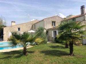 a house with two palm trees in front of it at Maison ancienne avec piscine au milieu des vignes 