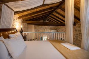 Schlafzimmer mit einem großen weißen Bett und Holzdecken in der Unterkunft Ktima Karageorgou in Areopoli