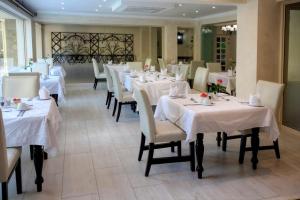 un comedor con mesas blancas y sillas blancas en 10 2ND AVENUE HOUGHTON ESTATE BOUTIQUE HOTEL en Johannesburgo