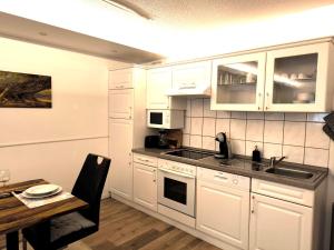 a kitchen with white cabinets and a table and a sink at Fewo BUDDY, 2 große Zimmer mit Balkon in Todtmoos