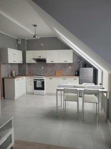 a kitchen with white cabinets and a table and chairs at Apartament Słowińców 52 in Wejherowo
