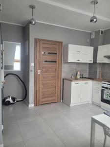 cocina con puerta de madera y armarios blancos en Apartament Słowińców 52 en Wejherowo