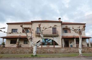 una casa grande con dos árboles delante de ella en Hotel Rural Centro de las Arribes en Aldeadávila de la Ribera