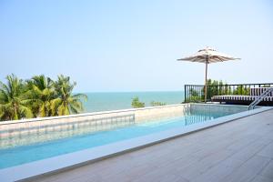 a swimming pool with an umbrella and the ocean at Dune Hua Hin Hotel in Hua Hin