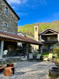 a stone building with chairs and a table in a yard at Grosszügige Dachwohnung in Tessiner Altbau in Monte Ceneri