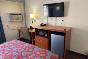 Habitación de hotel con cama y escritorio con TV. en Econo Lodge, en Waite Park