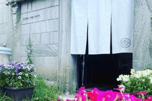 a door to a building with flowers in front of it at 石と鉄-House of STONE and IRON in Otaru