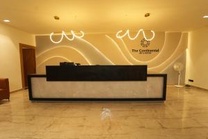 a reception desk in a lobby with a sign on the wall at THE CONTINENTAL INN & SUITES in Mysore