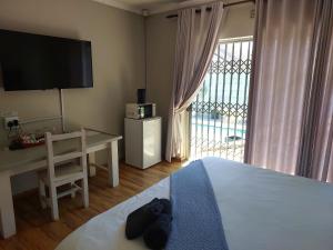 a bedroom with a bed and a desk and a television at UNIQUE BnB in Vryheid +19 photos