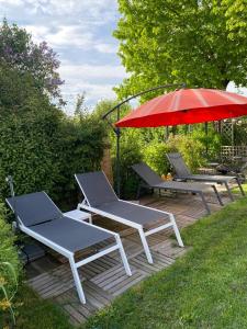 twee stoelen en een parasol op een houten terras bij Aux Lacs et Cascades in Songeson