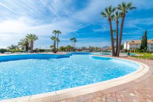 a swimming pool with palm trees in a resort at Sunny Golden 1BDR Apartment w Beach & Pool Access Included in Cabanas de Tavira +17 photos