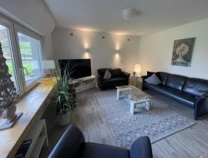 a living room with a black leather couch and a tv at Gästehaus An der Berbke in Arnsberg