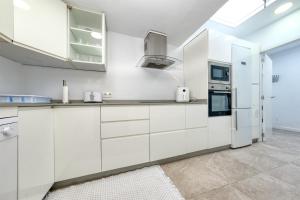a white kitchen with white cabinets and appliances at Sol Y Arena Playa Honda-100m from the beach in Playa Honda