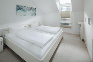 a white bed in a white room with a window at Ferienhaus Haus an der Mühle in Norderney