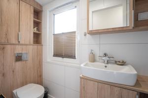 ein Badezimmer mit Waschbecken und Toilette und einem Fenster in der Unterkunft Ostseecamp Ferienhaus "Sonneneck" mit umzäuntem Grundstück in Scharbeutz + 23 Fotos