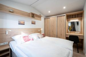 ein Schlafzimmer mit einem großen weißen Bett und einem Schrank in der Unterkunft Ostseecamp Ferienhaus "Sonneneck" mit umzäuntem Grundstück in Scharbeutz
