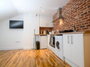 a kitchen with white cabinets and a brick wall at Pass the Keys Cathedral View Apartment Two in Lincoln