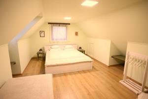 ein Schlafzimmer mit einem weißen Bett im Dachgeschoss in der Unterkunft Góhér pince és vendégház in Császártöltés